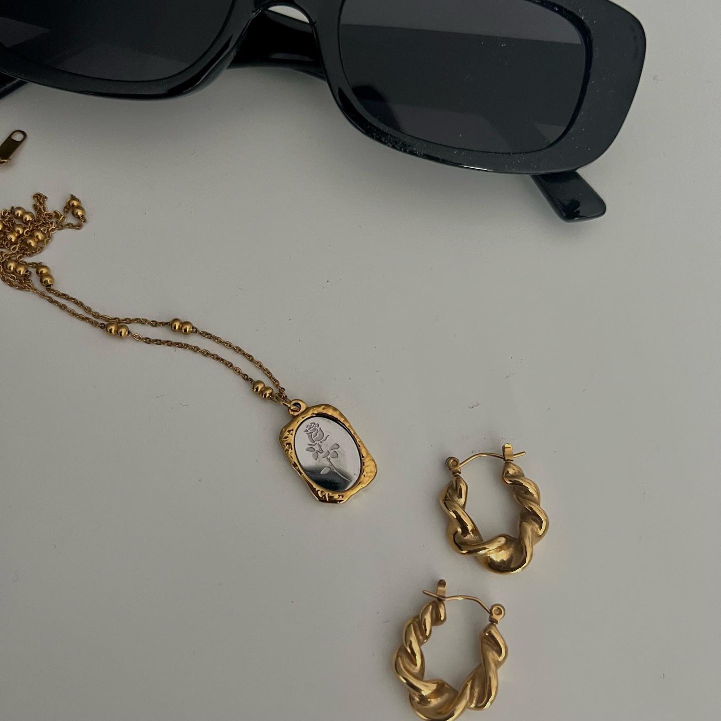 A gold chain necklace styled with sunglasses