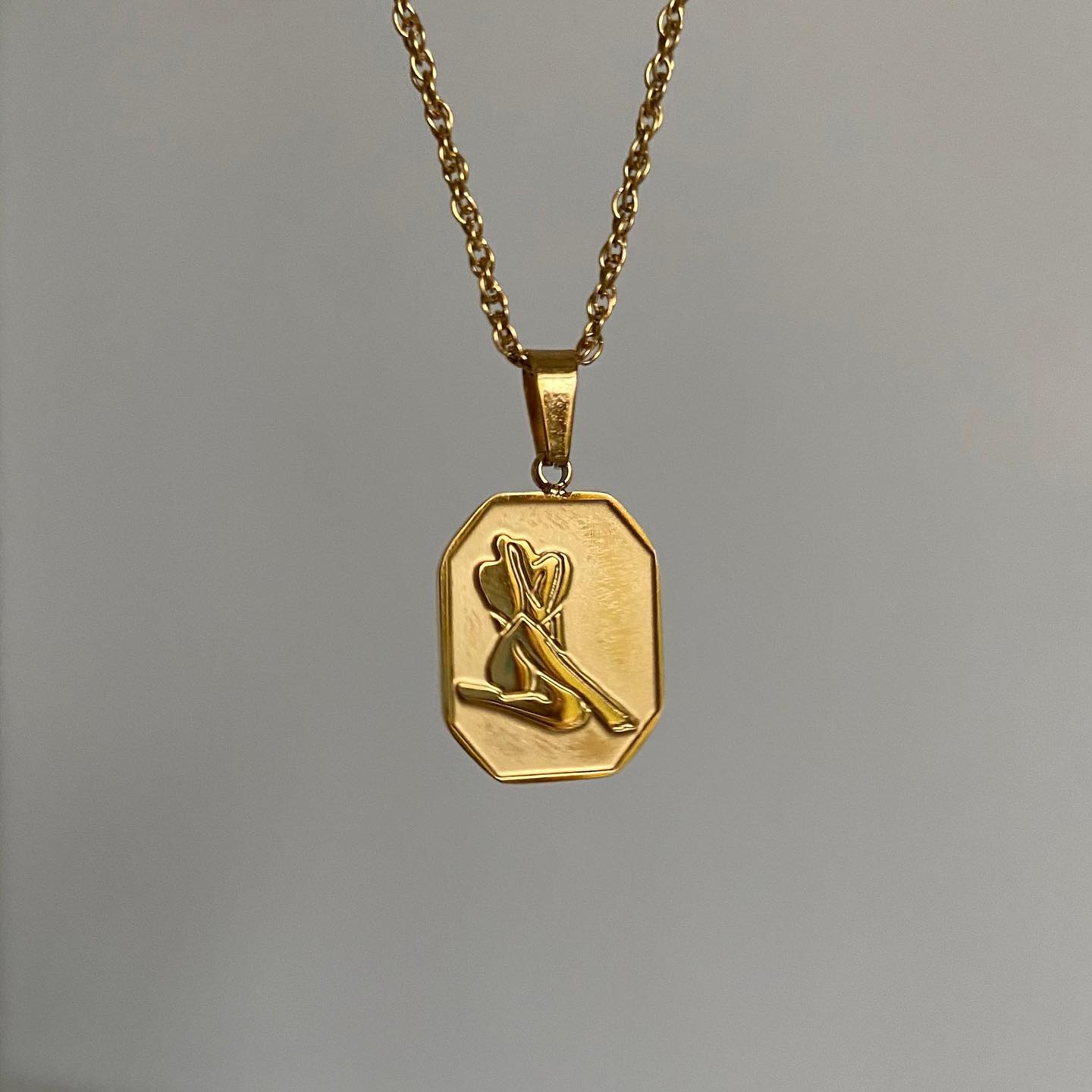 A gold pendant necklace with a charm